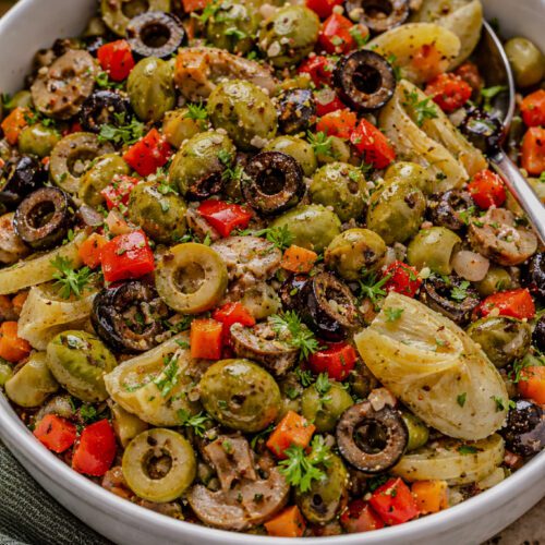 Homemade olive salad with green olives, black olives, artichoke hearts, peppers, and fresh parsley