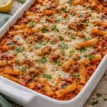 Baked ziti with melted mozzarella and rich tomato sauce in a white baking dish