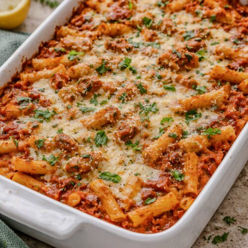 Baked ziti with melted mozzarella and rich tomato sauce in a white baking dish