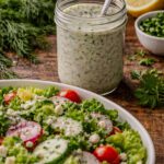 Mason jar filled with creamy buttermilk dill dressing with fresh dill and herbs