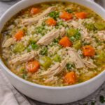 Bowl of homemade chicken and rice soup with tender chicken, vegetables, and rice added at serving time