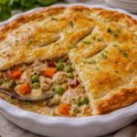 Homemade chicken pot pie with golden flaky crust and creamy vegetable filling in a white pie dish