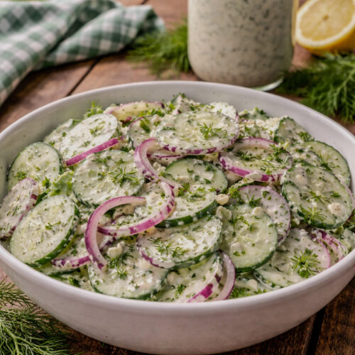 Creamy cucumber salad with fresh dill and red onion in a bowl