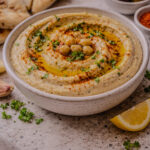 Bowl of Israeli hummus drizzled with olive oil and topped with paprika and parsley