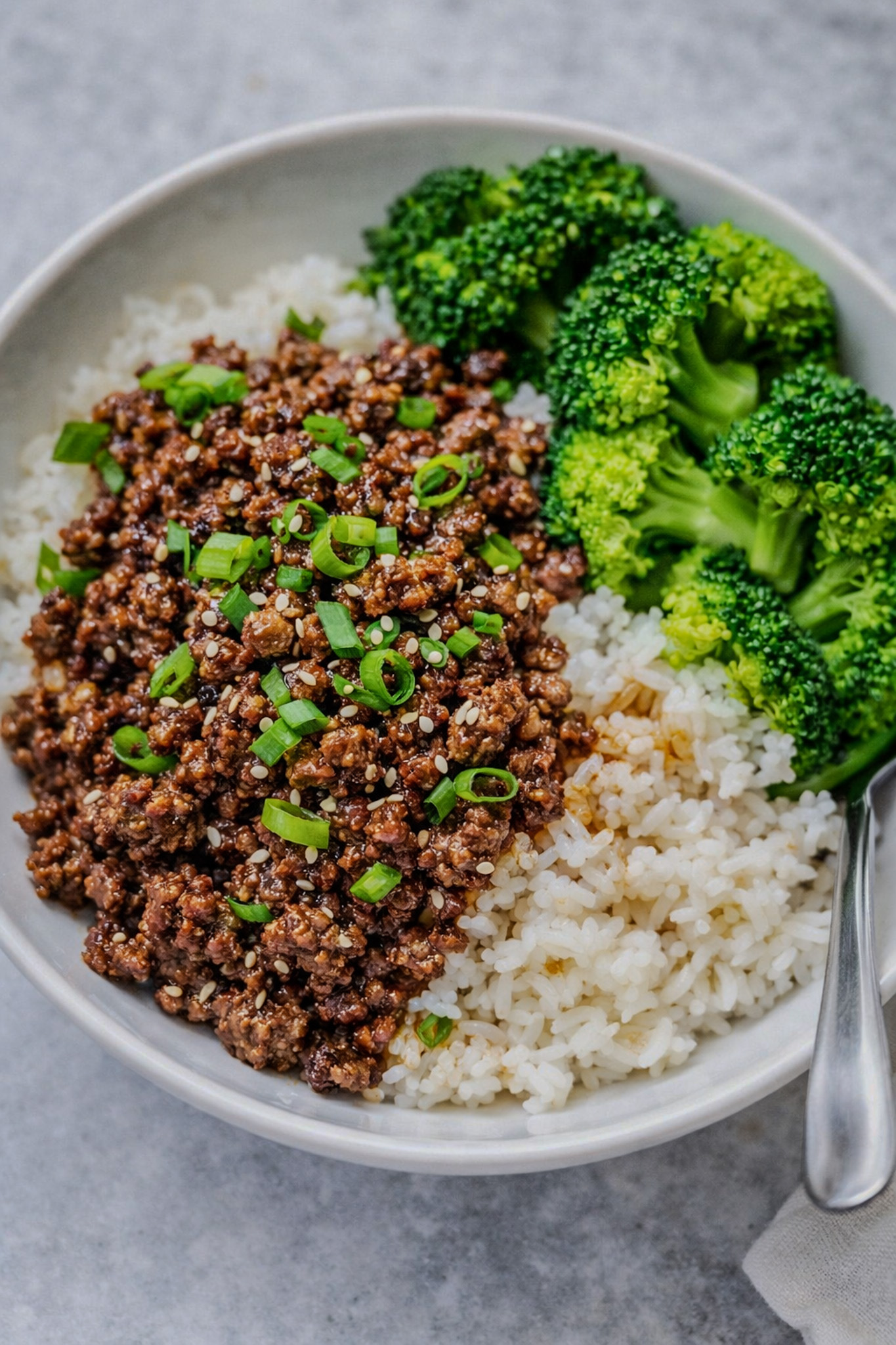 Korean ground beef and broccoli served over rice with green onions and sesame seeds