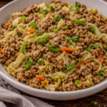 Pork fried cauliflower rice with ground pork, cabbage, carrots, and green onions cooked in a skillet