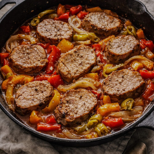 Seared pork tenderloin slices with sweet bell peppers and pepperoncini in a skillet