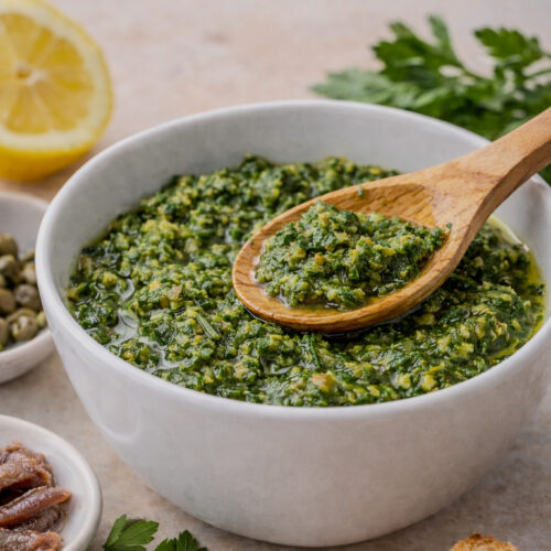 Italian salsa verde made with parsley, capers, anchovies, and olive oil in a bowl with spoon.