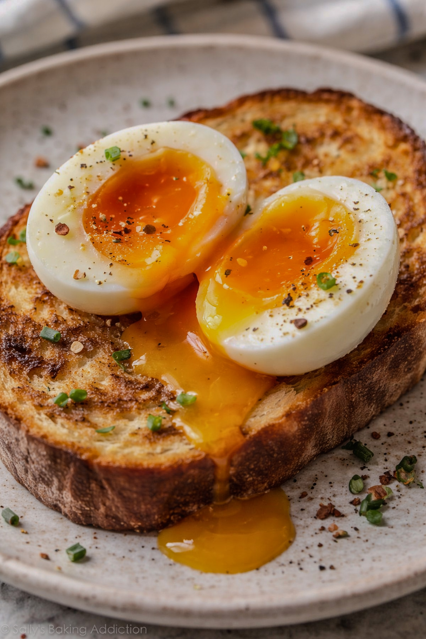 Soft-boiled egg cut in half over toast with runny yolk flowing onto the bread.