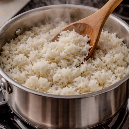 Steaming white rice cooking in a stainless steel pot on the stovetop