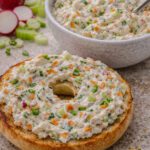 Homemade vegetable cream cheese spread with carrots, scallions, radish, and celery served on a bagel