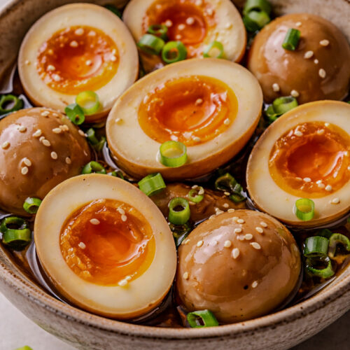 Ajitama eggs sliced in half showing jammy yolks and soy-marinated bronze whites.
