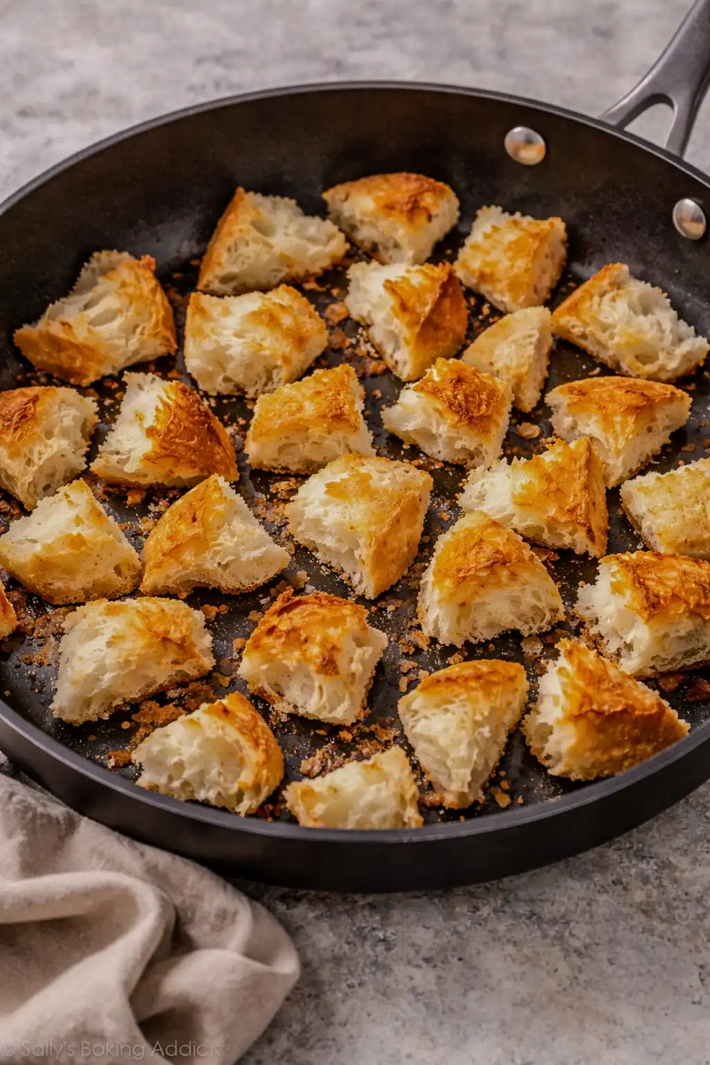 Torn pieces of bread toasting in a skillet until golden and crispy for breadcrumb pasta.