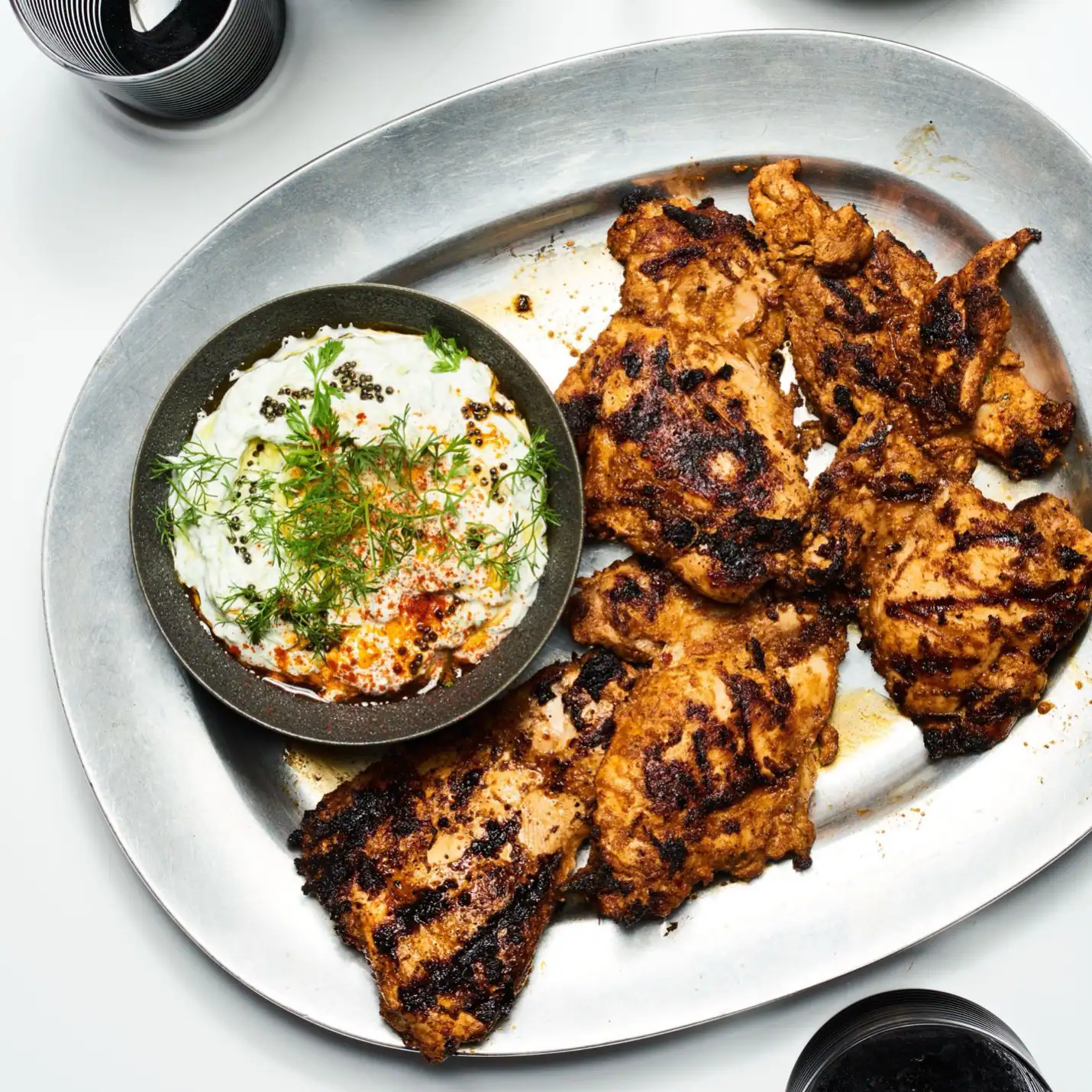 A plate of perfectly grilled chicken pieces accompanied by a creamy herb yogurt sauce, ideal for healthy eating and flavorful dining.